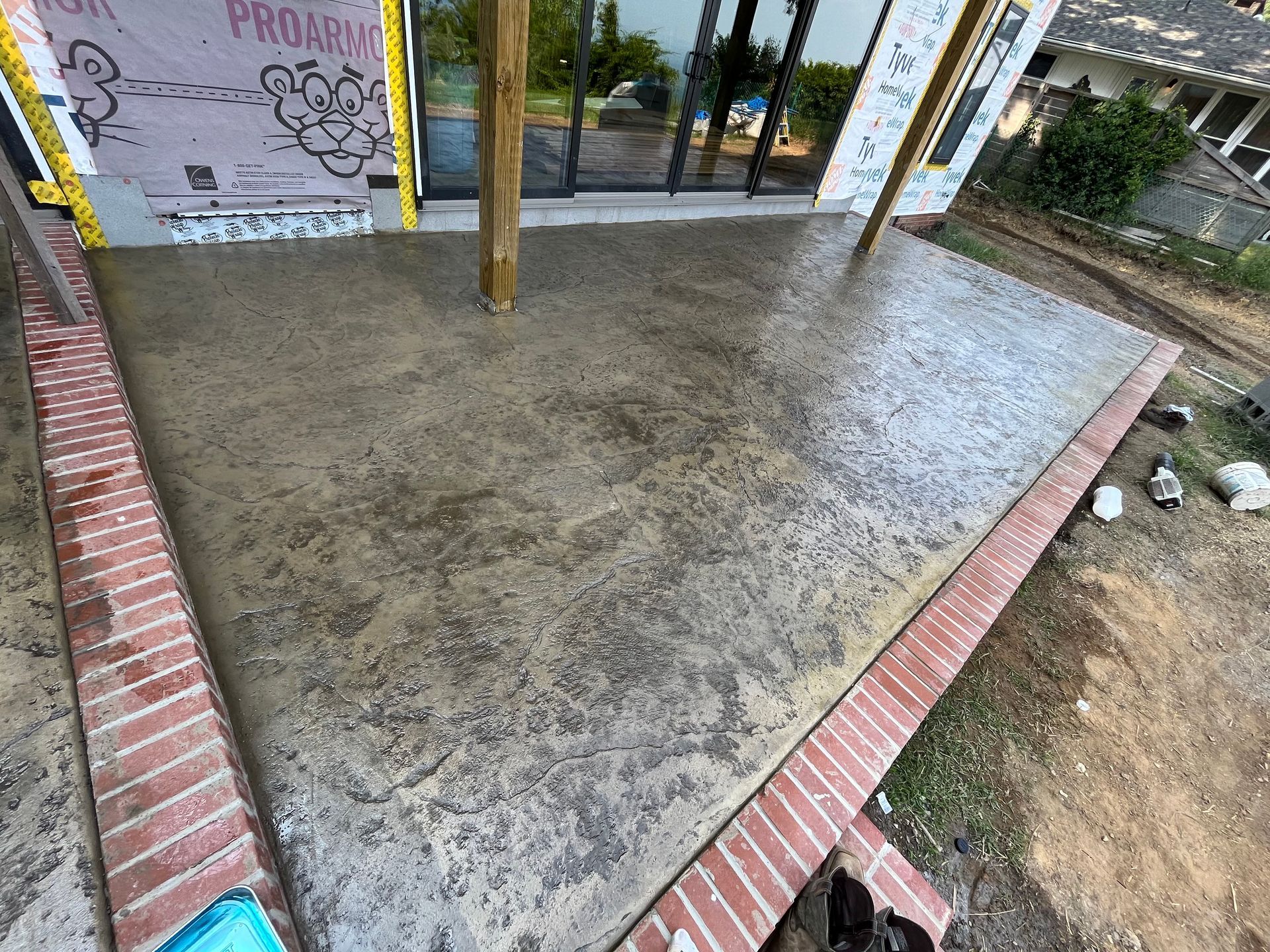 A concrete deck with a brick border is being built on top of a house.