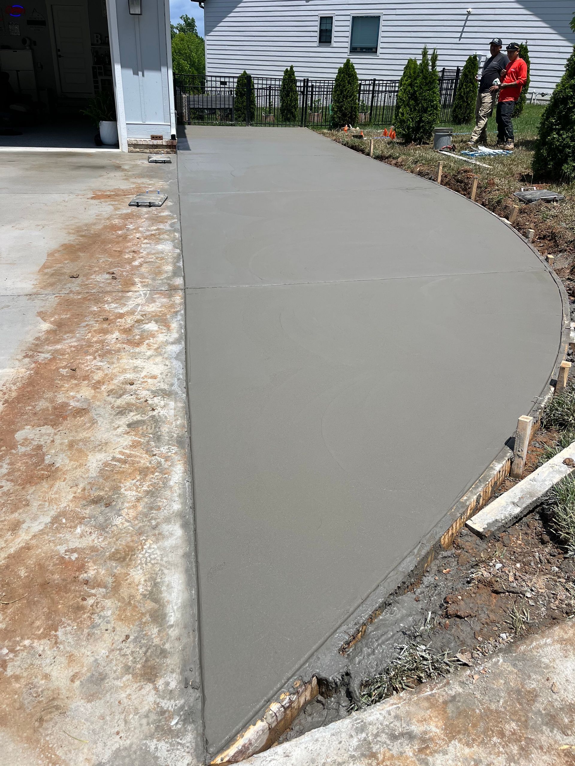 A concrete driveway is being built in front of a house.