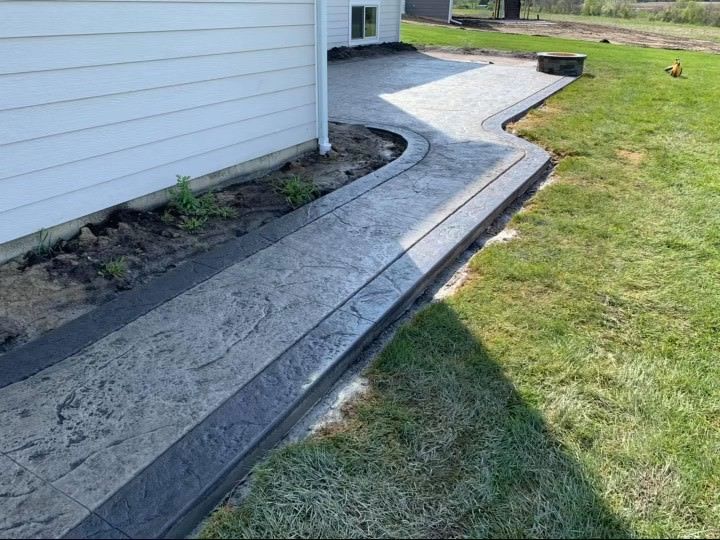 A concrete walkway is being built in the backyard of a house.