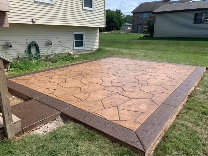 A concrete patio in front of a house with a house in the background.