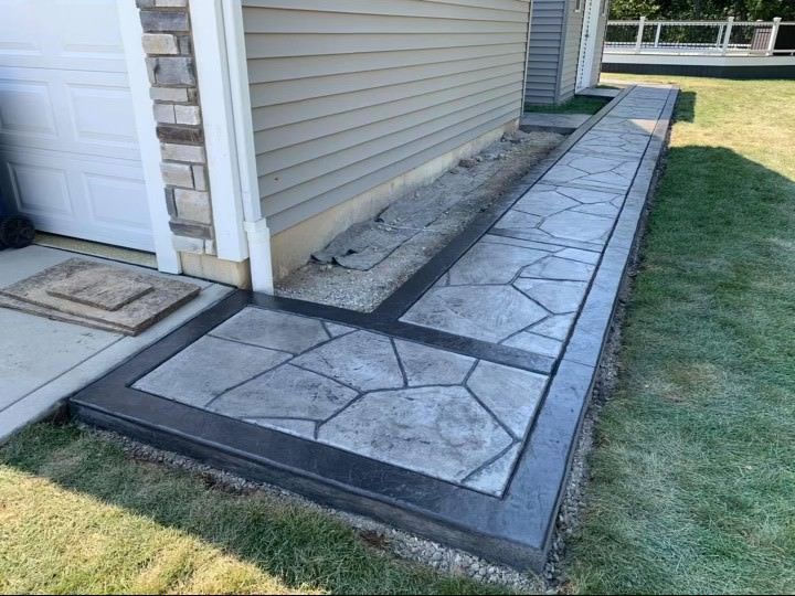 A concrete walkway leading to a garage next to a house.