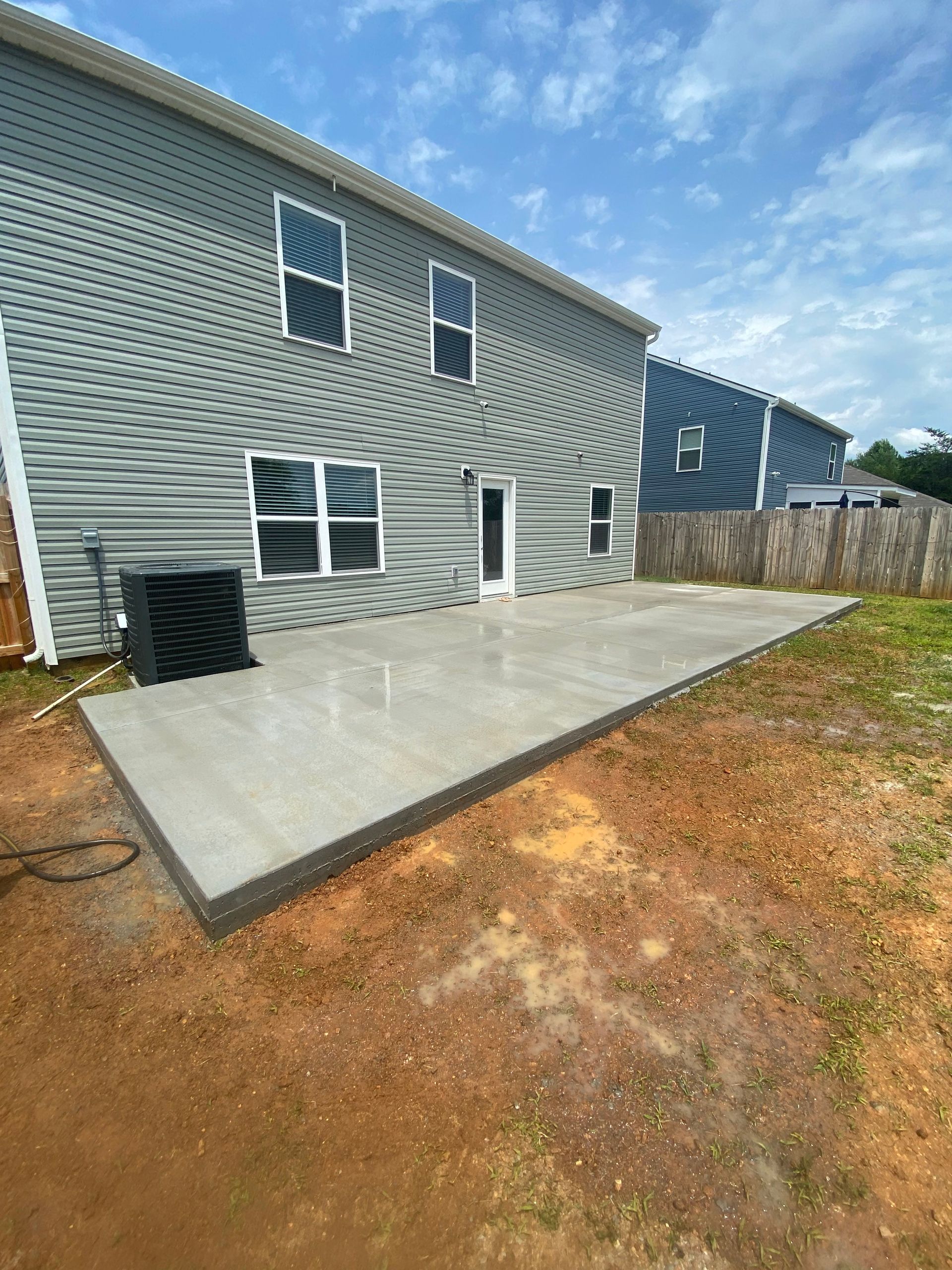 A concrete patio is being built in the backyard of a house.