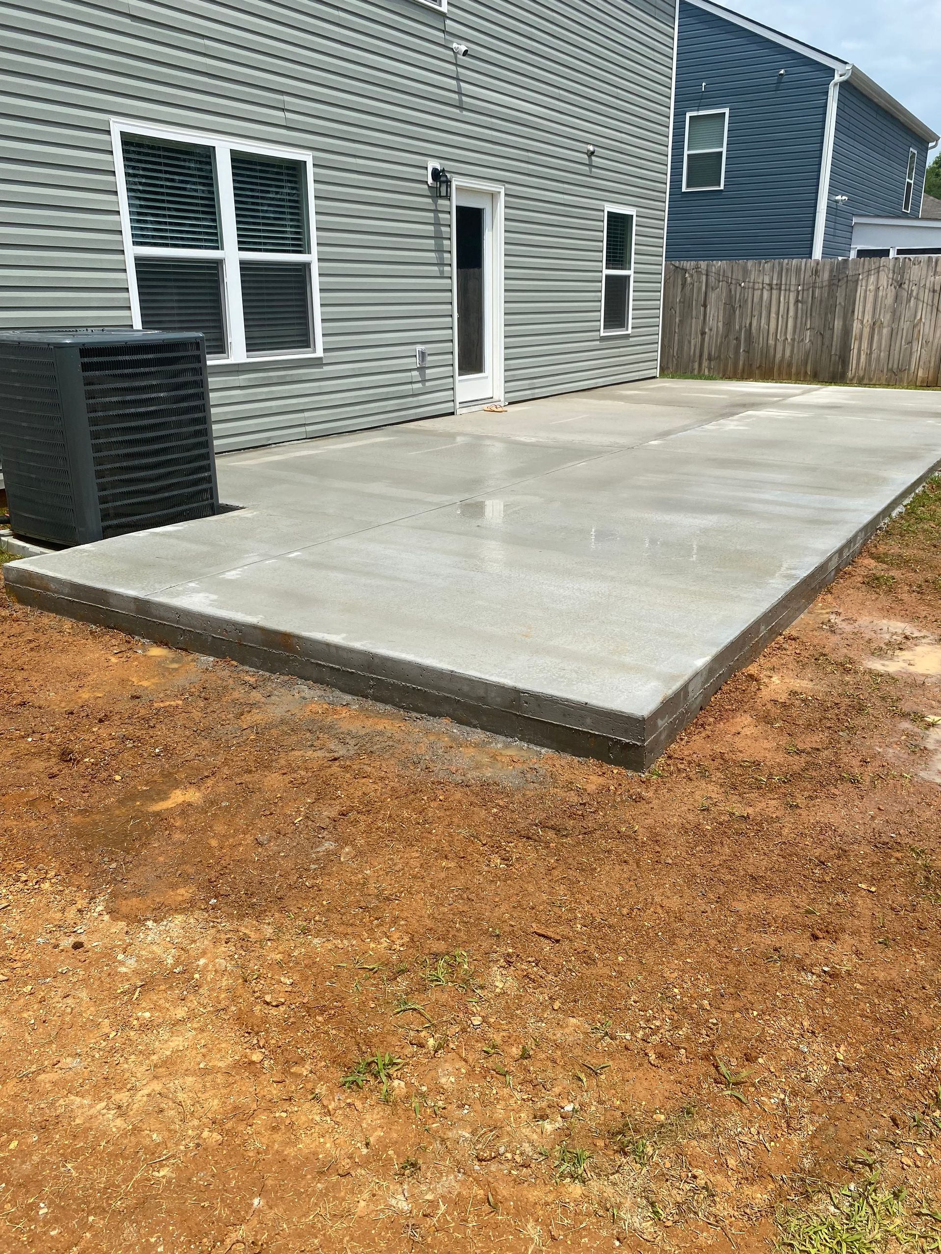 A concrete patio is being built in front of a house.