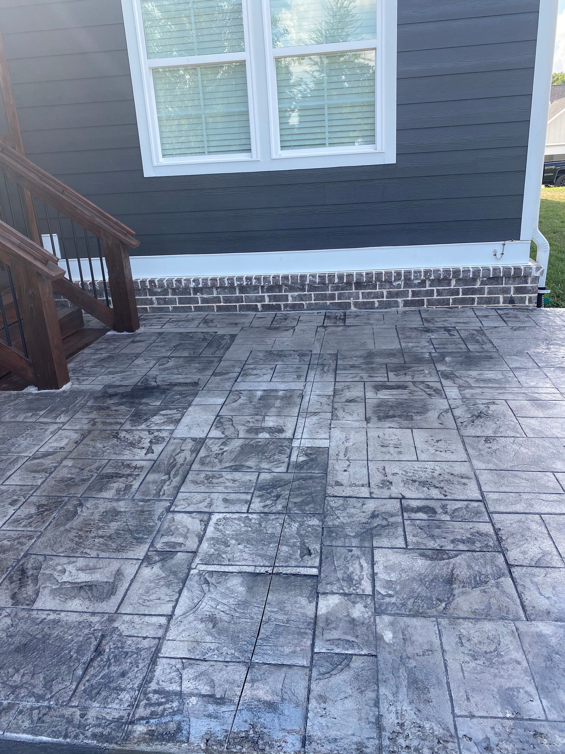 A concrete patio with stairs leading up to a house.