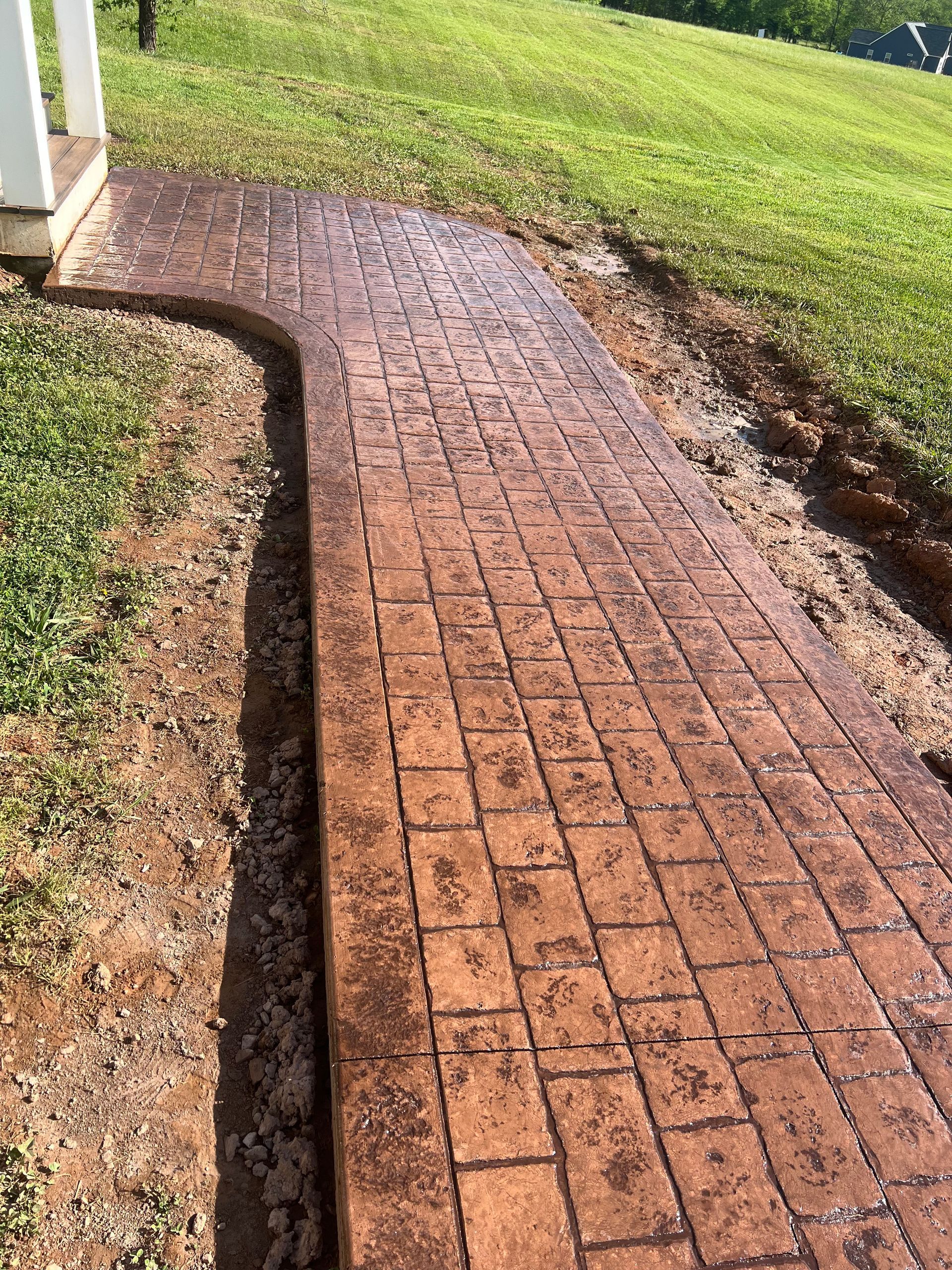 A brick walkway is going through a grassy field.