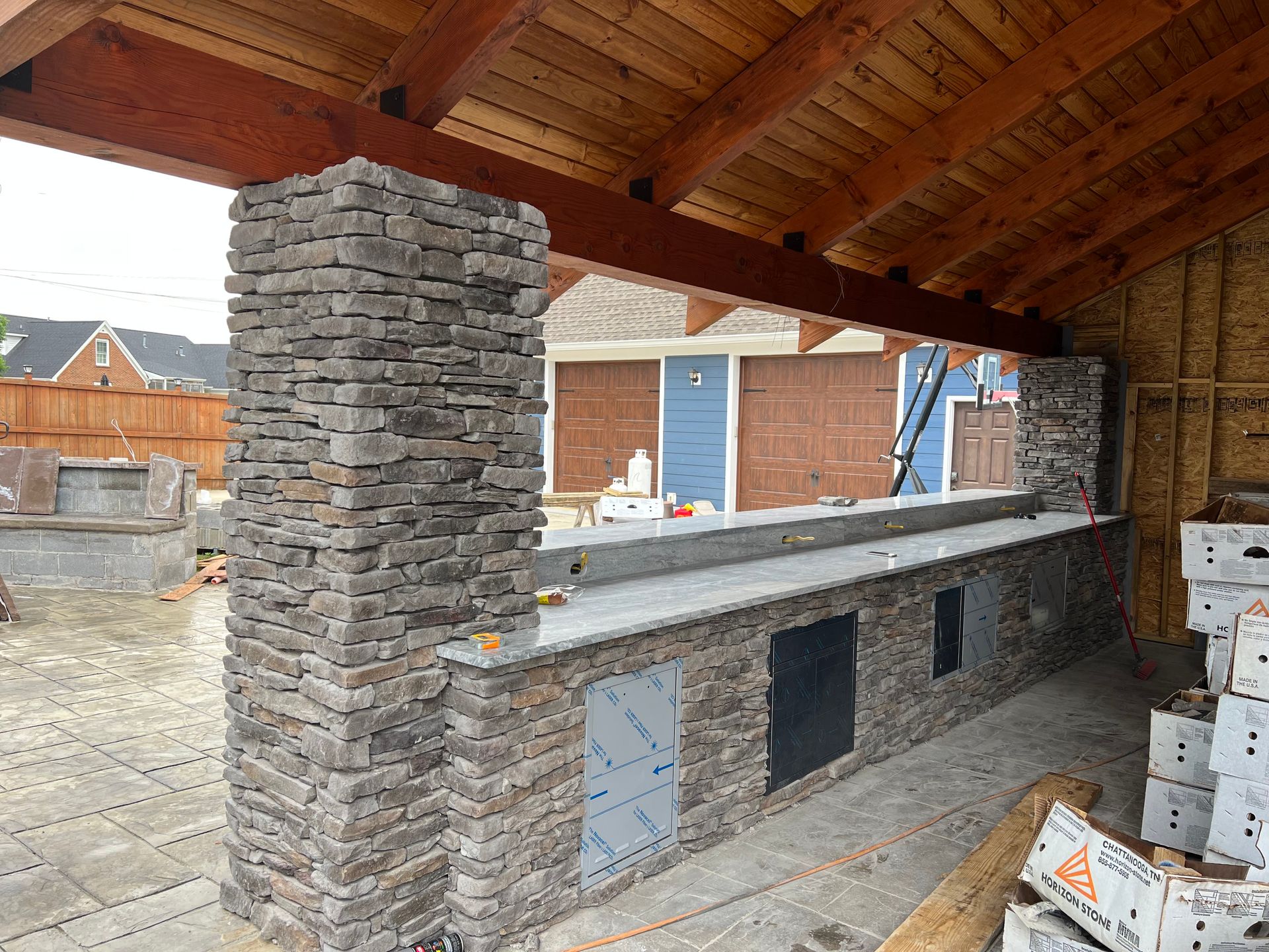 A building under construction with a wooden roof and a stone wall.
