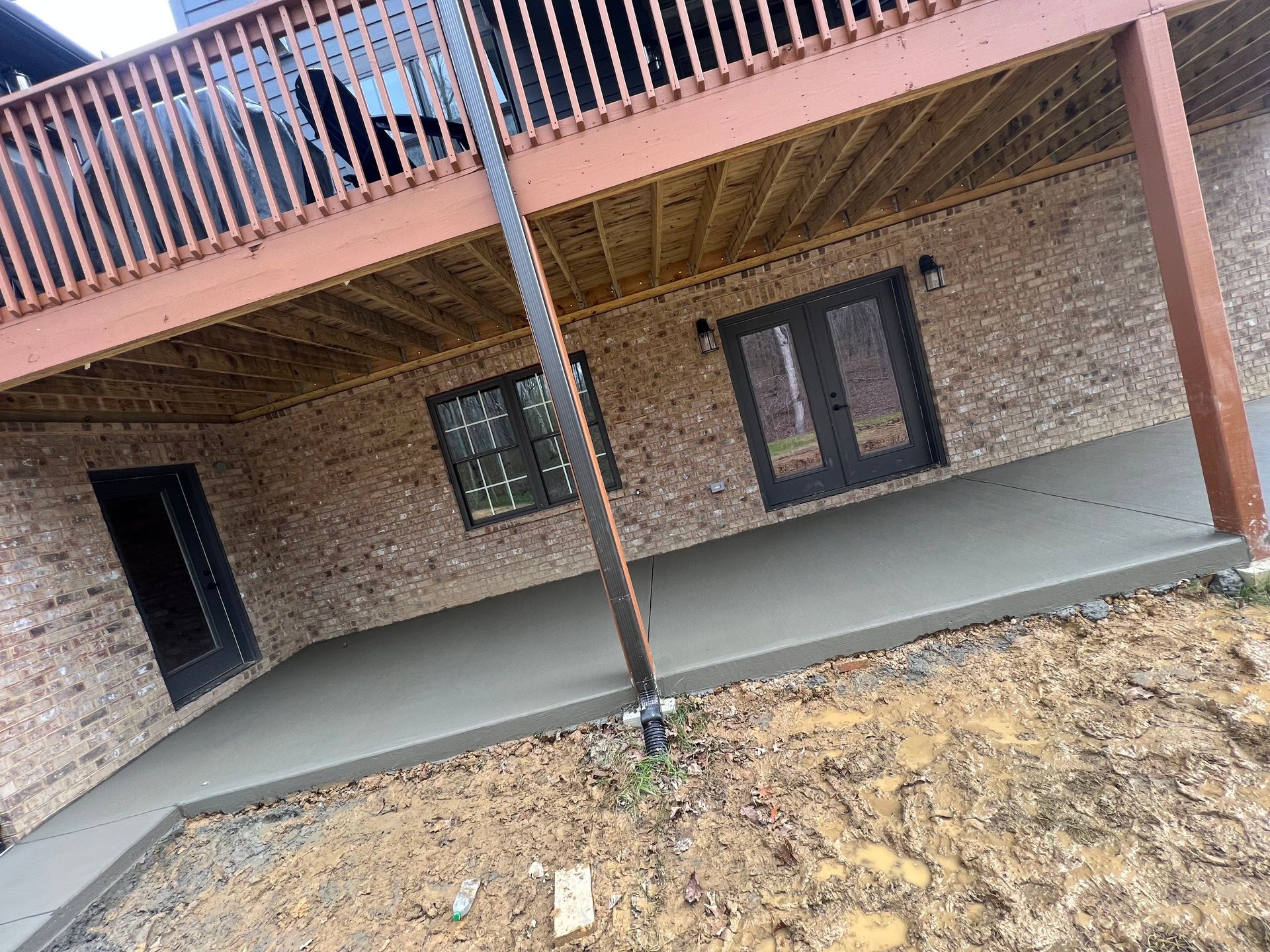 A brick house with a wooden deck and a concrete patio.