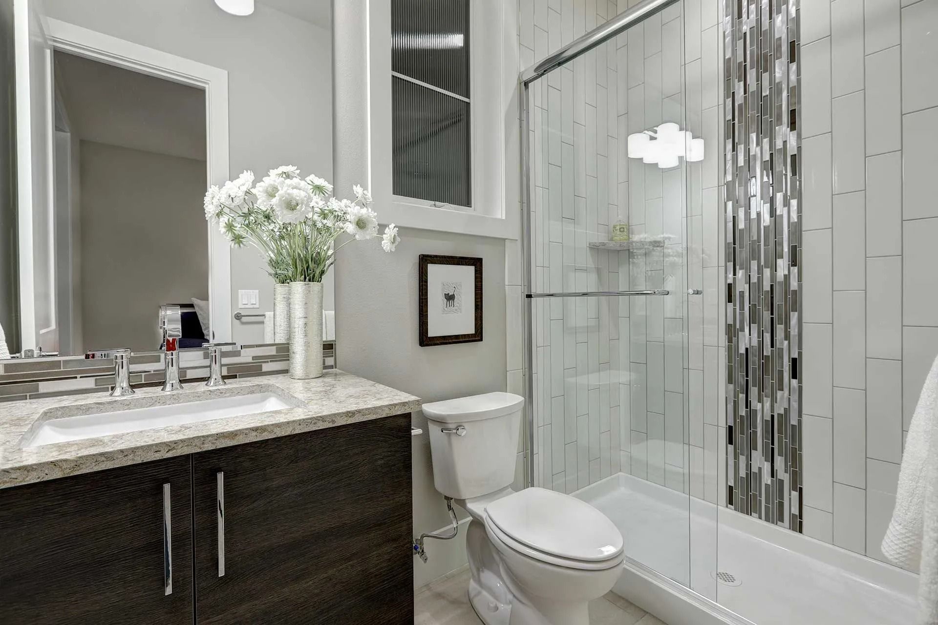 Modern bathroom with gray walls, white fixtures, and a glass shower.