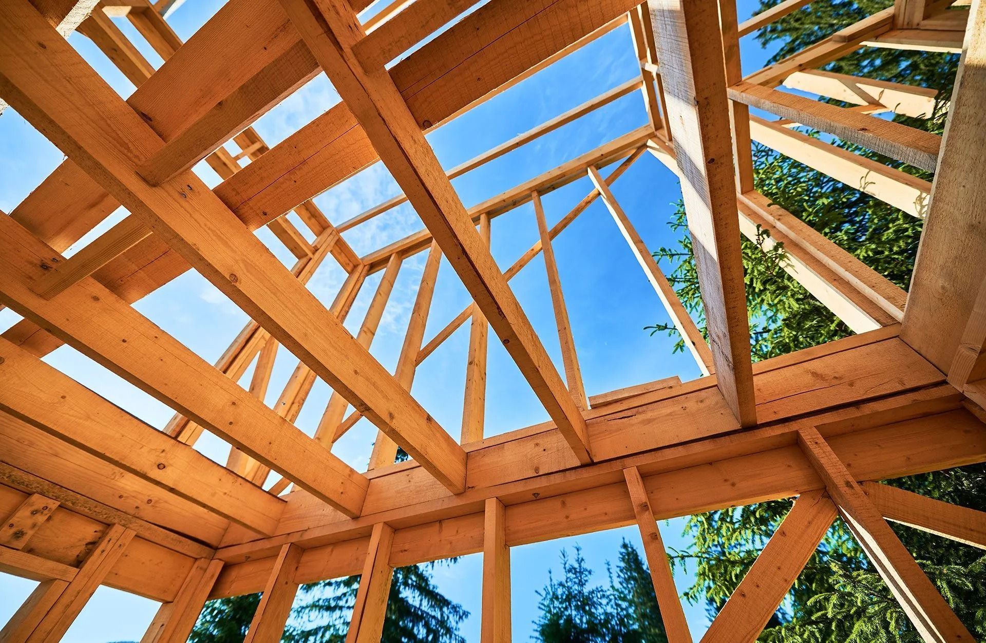 Wooden roof frame under construction, clear blue sky visible.