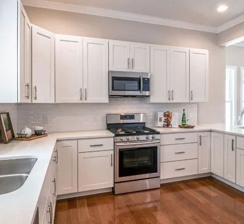 White kitchen with stainless steel appliances, white cabinets, and white countertops.