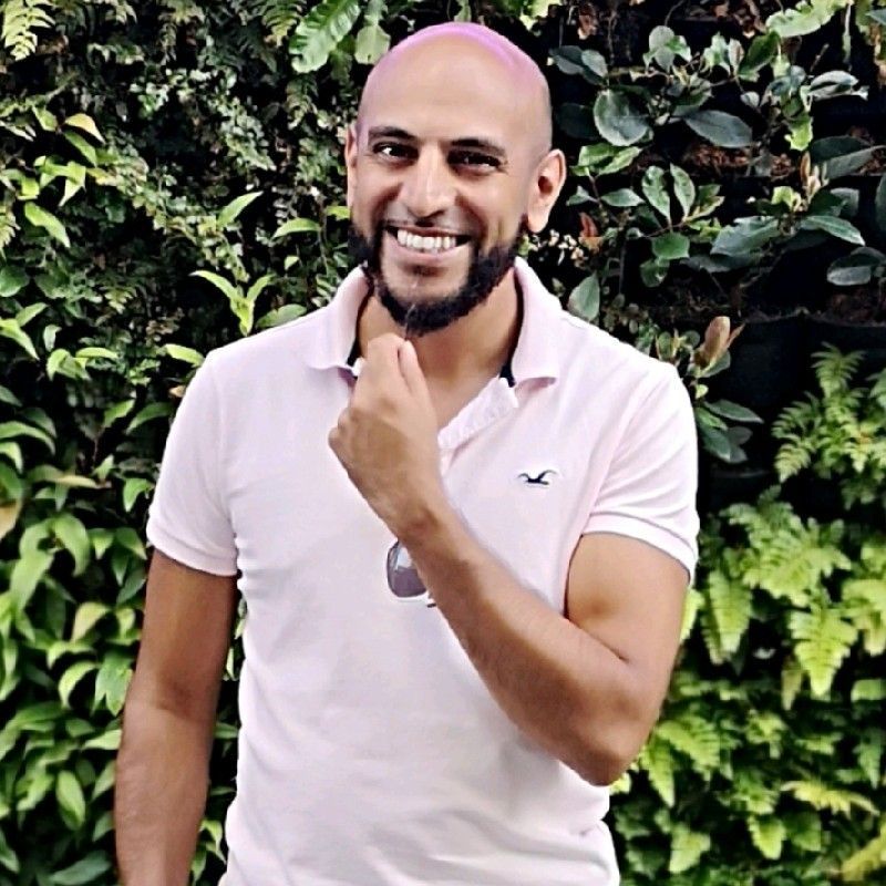 A bald man with pink hair is wearing a pink polo shirt