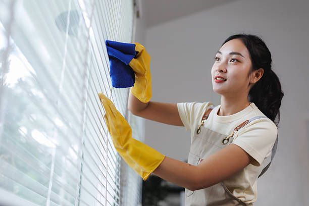 Silhouette of a woman looking out a window with bamboo blinds.