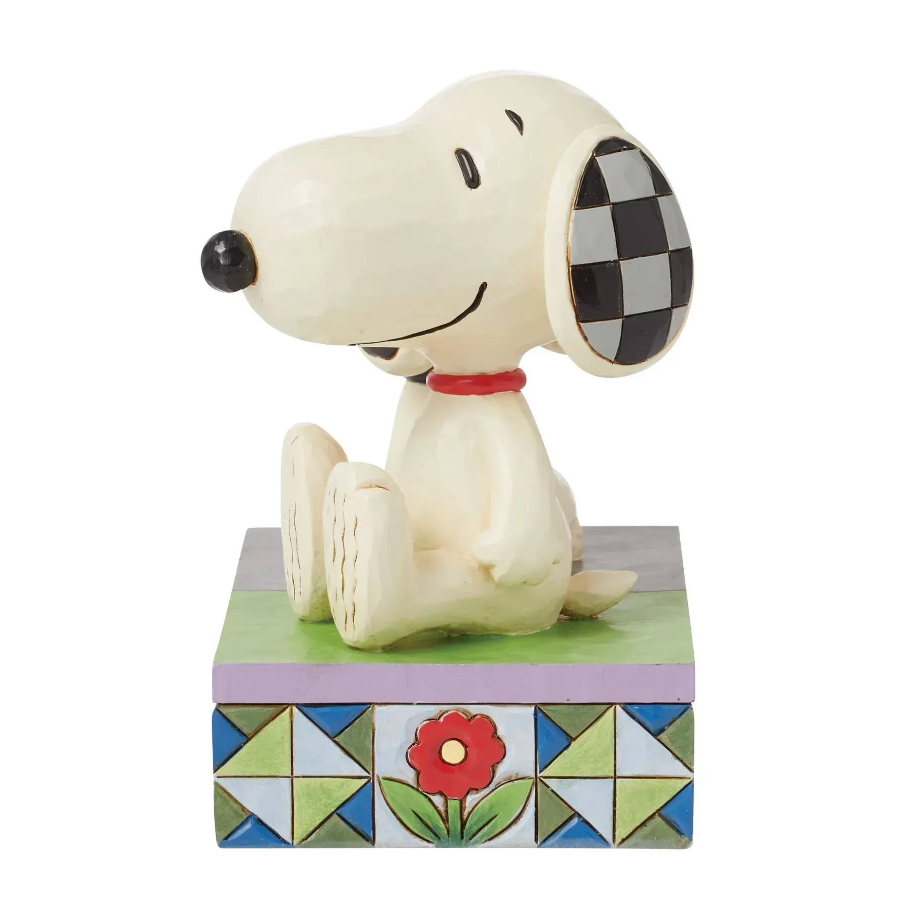 Een beeldje van snoopy zit op een doos met een bloem erop.