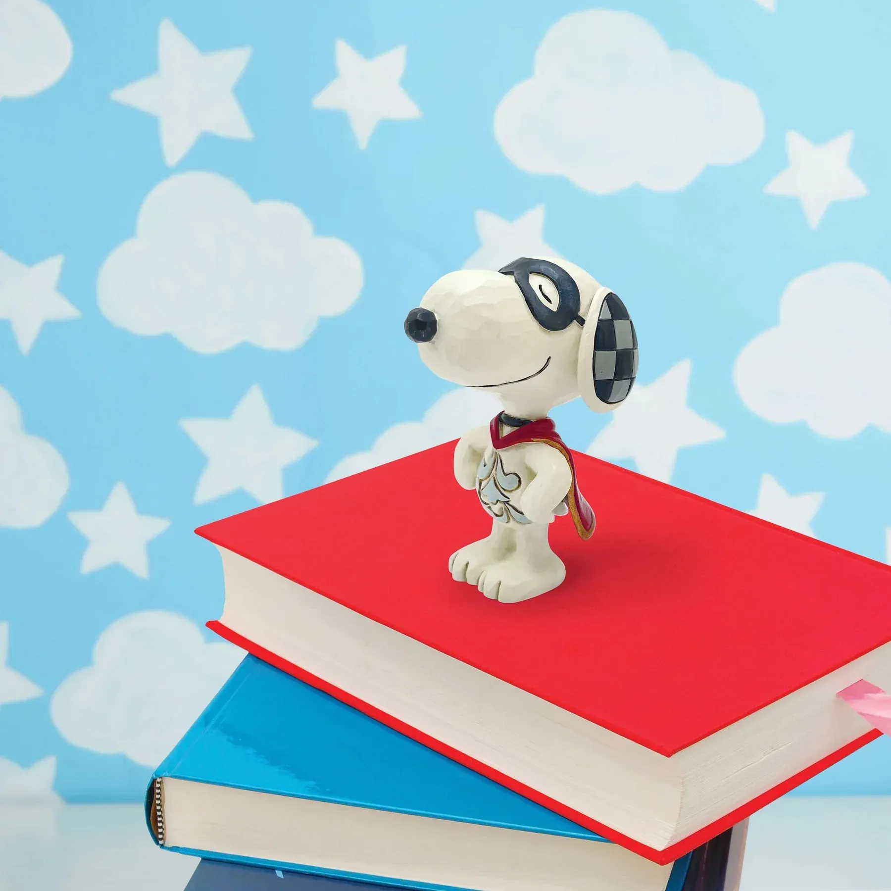 Een snoopy-figuurtje zit bovenop een stapel boeken
