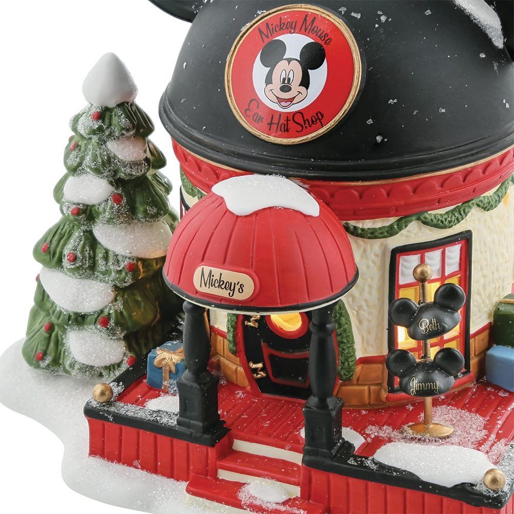 Een kerstdorpje met Mickey Mouse's hoedenwinkel, een besneeuwd dak en een kerstboom.
