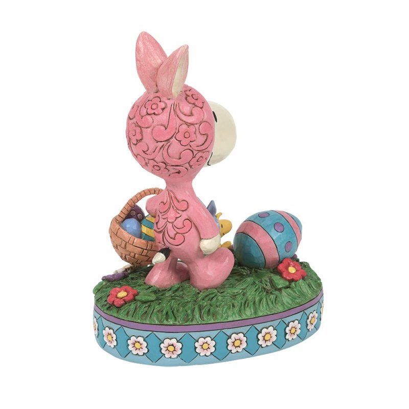 Een roze konijnenbeeldje houdt een mandje met paaseieren vast.