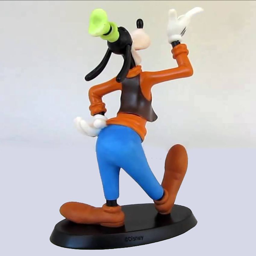 Een grappig figuurtje in een oranje shirt, blauwe broek en bruine schoenen, dat lachend omhoog wijst.