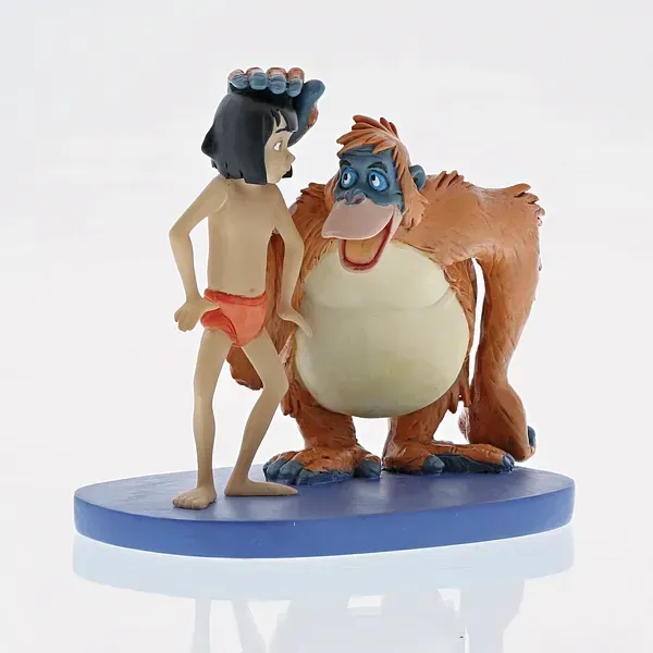 Mowgli en King Louie beeldjes. Mowgli in een oranje lendendoek en Louie in een bruine vacht op een blauwe sokkel.