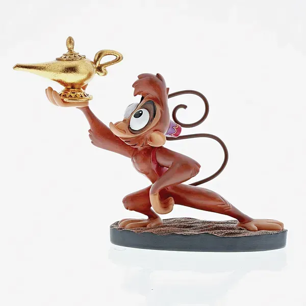 Abu, de aapfiguur, houdt een gouden lamp vast en knielt op een sokkel met structuur.