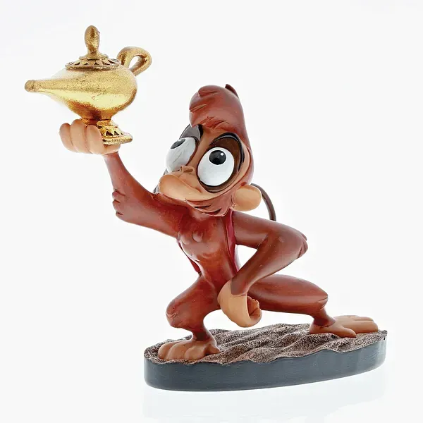 Het beeldje van aapje Abu, die een gouden lamp vasthoudt, zit gehurkt en heeft een verbaasde uitdrukking.