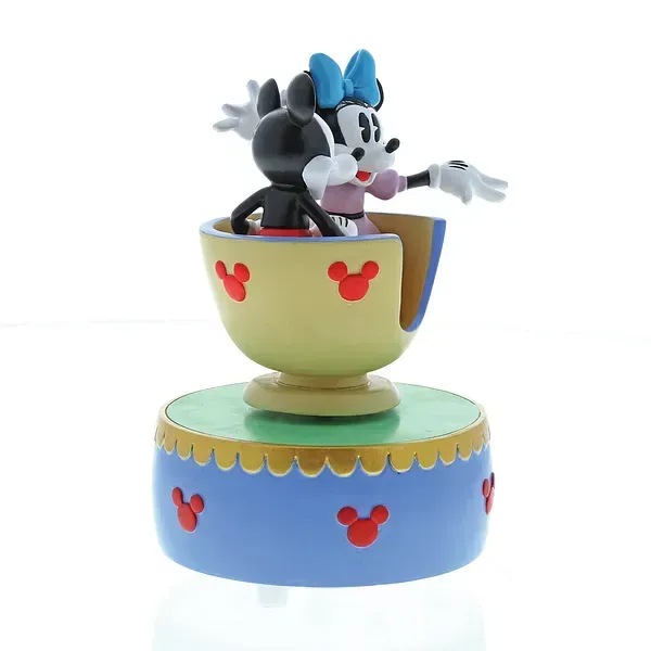 Mickey en Minnie Mouse-figuurtjes in een theekopje, op een blauwe voet versierd met Mickey Mouse-pictogrammen.