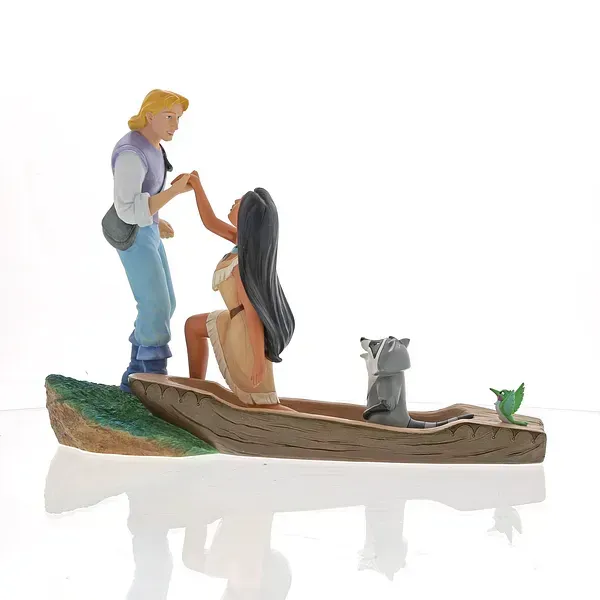 Beeldjes van Pocahontas en John Smith. Zij knielt in een kano en houdt zijn hand vast. Wasbeer Meeko kijkt toe.