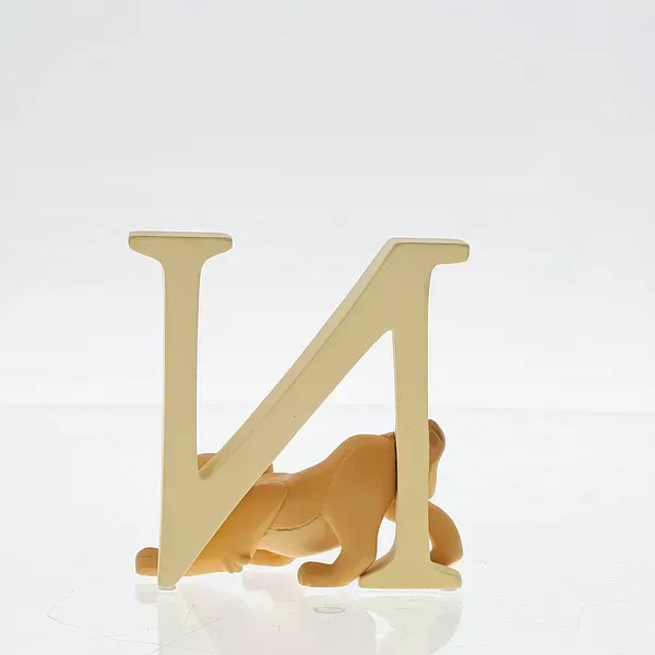 Leeuwenwelpje Nala klampt zich vast aan een crèmekleurige letter