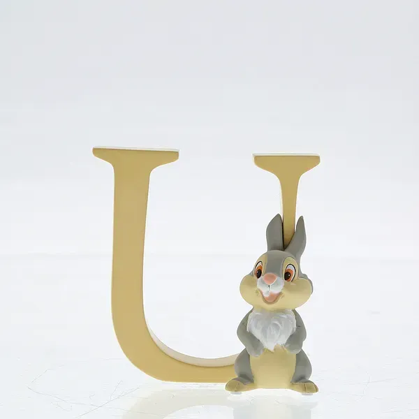 Het figuurtje van Stampertje uit Bambi staat naast een gele houten letter