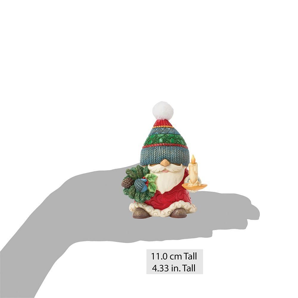 Een beeldje van de kerstman met een krans en een kaars