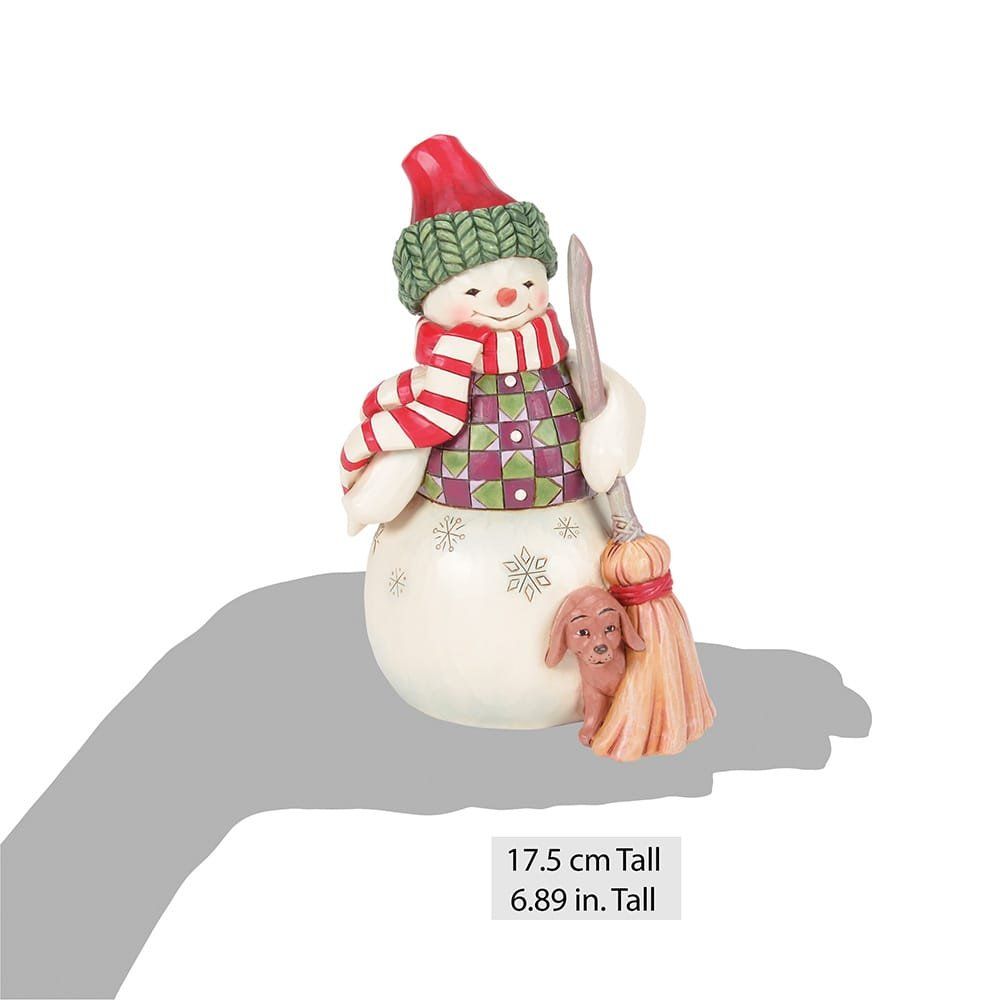 Een sneeuwman houdt een bezem en een hond vast.