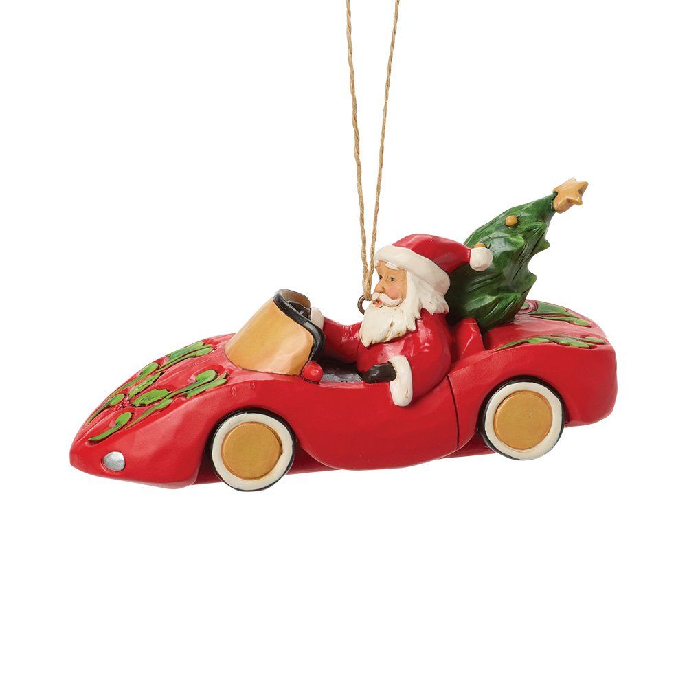 De kerstman rijdt in een rode auto met een kerstboom achterop