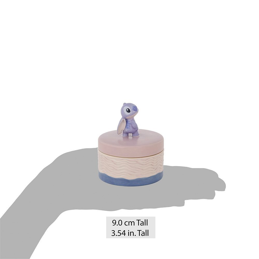 Een klein, rond sieradendoosje met een paarse cartoonvogel erop.