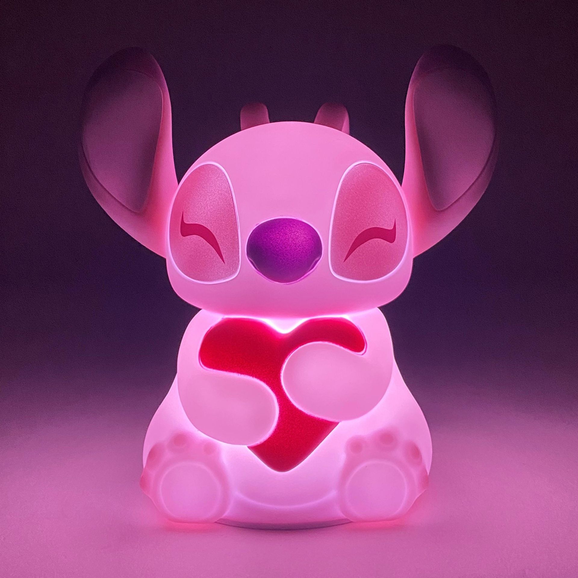 Een roze, oplichtende Stitch houdt een rood hart vast.