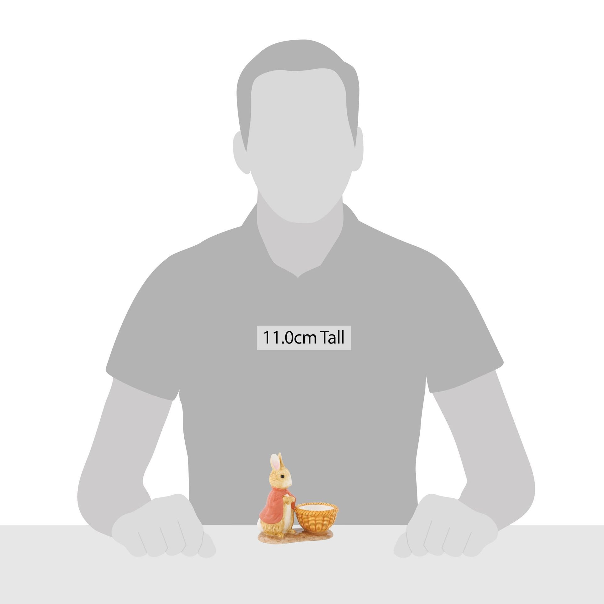 Een man zit aan een tafel met een beeldje van een konijn in een mand.