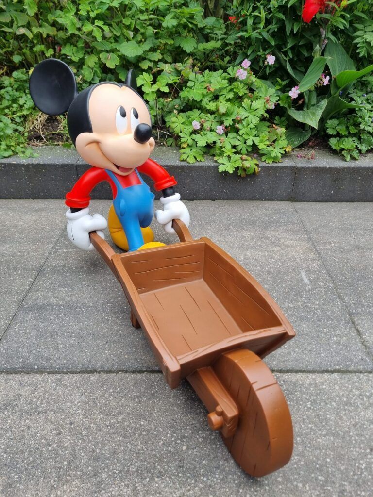 Een standbeeld van Mickey Mouse duwt een kruiwagen