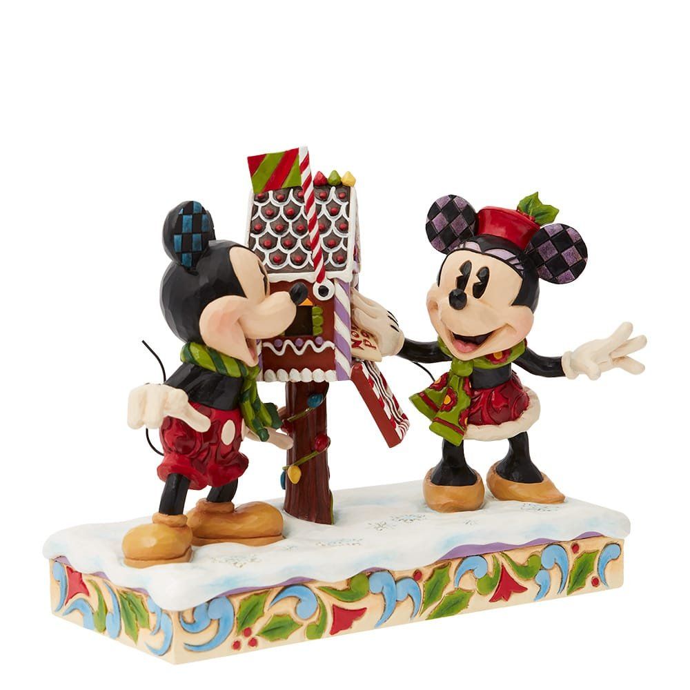 Mickey Mouse en Minnie Mouse staan naast elkaar voor een peperkoekenhuisje.