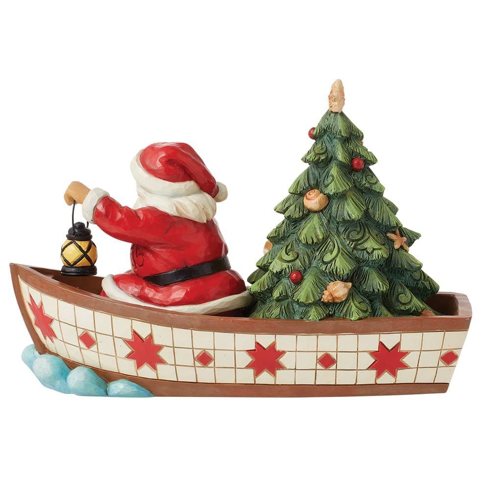 Een beeldje van de kerstman in een boot met een kerstboom.