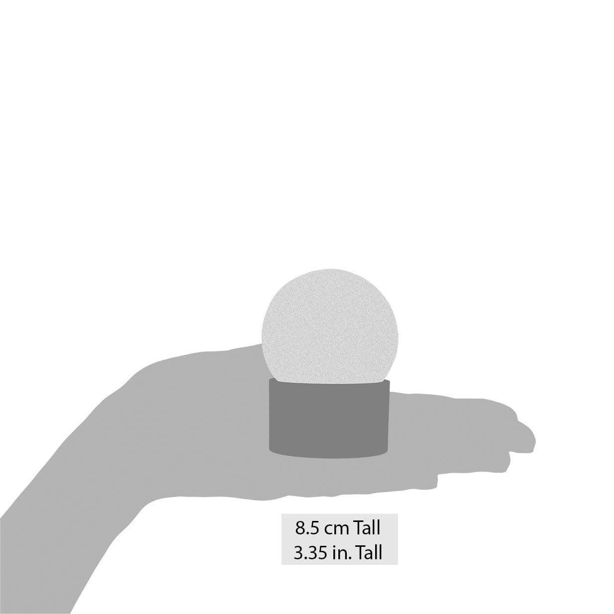 Een hand houdt een kleine sneeuwbol vast die 3,5 inch hoog is.