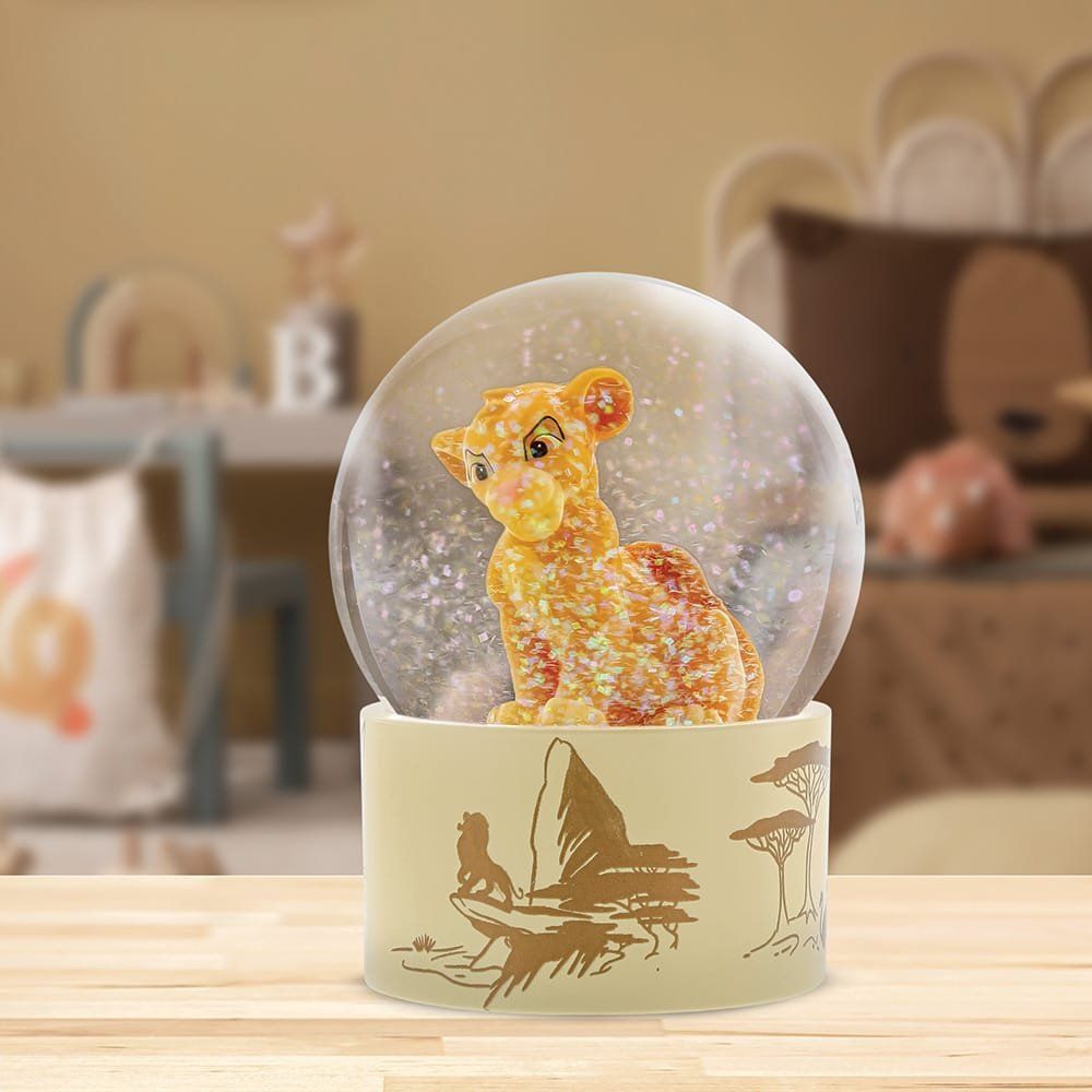 Op een houten tafel staat een sneeuwbol met daarin een leeuw.