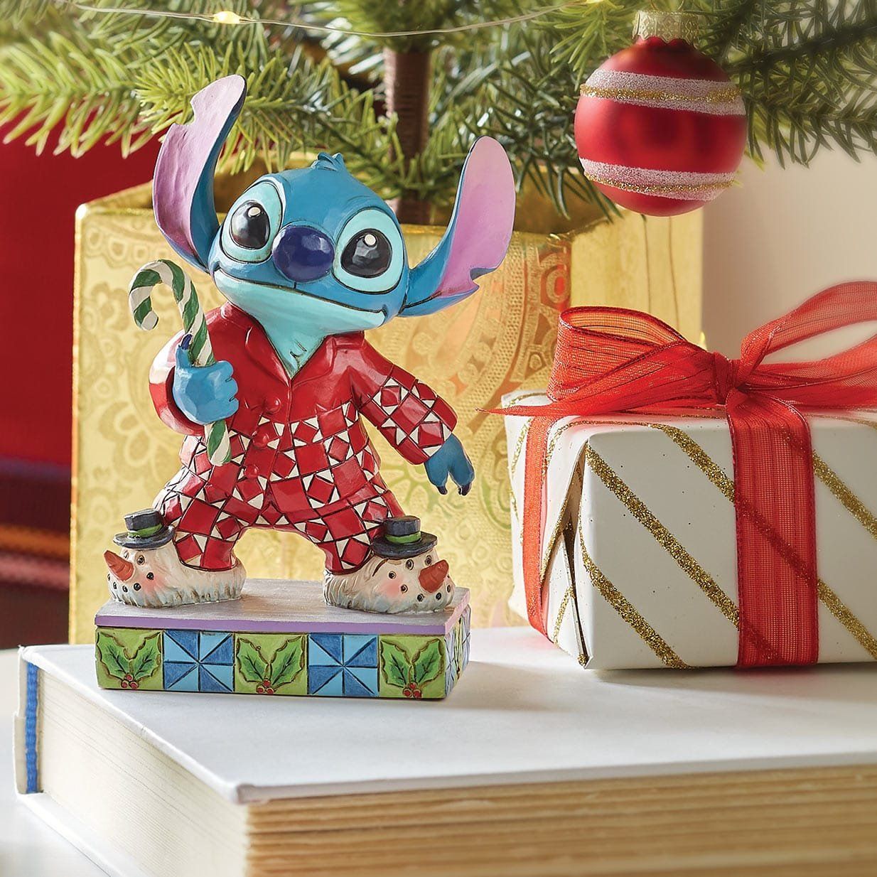 Een beeldje van Stitch houdt een zuurstok vast voor een kerstboom.