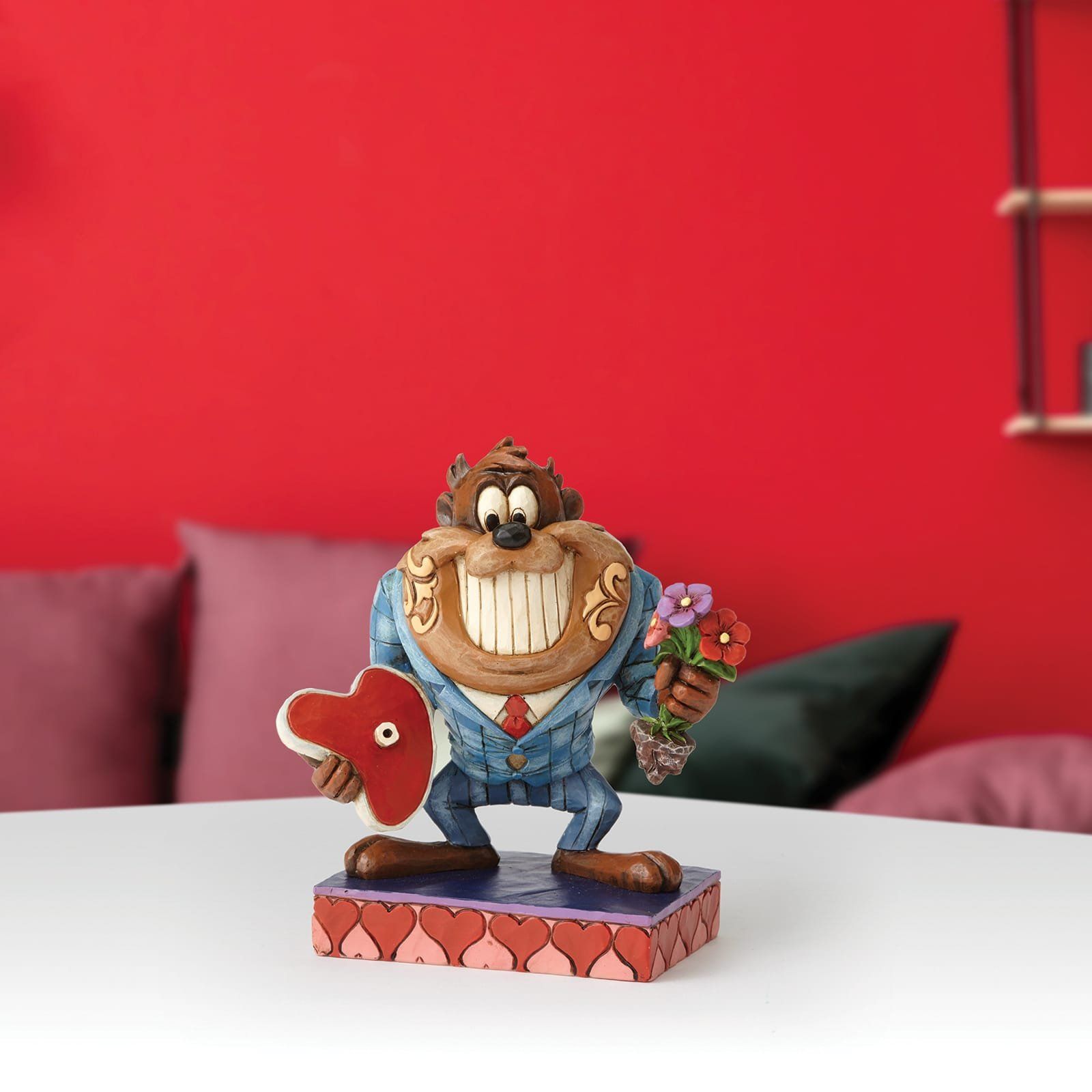 Een standbeeld van taz die een hart en bloemen vasthoudt staat op een tafel.