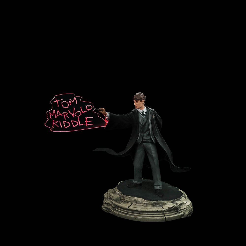 Een standbeeld van harry potter die een toverstok vasthoudt met de woorden ``tom riddle'' erop geschreven.