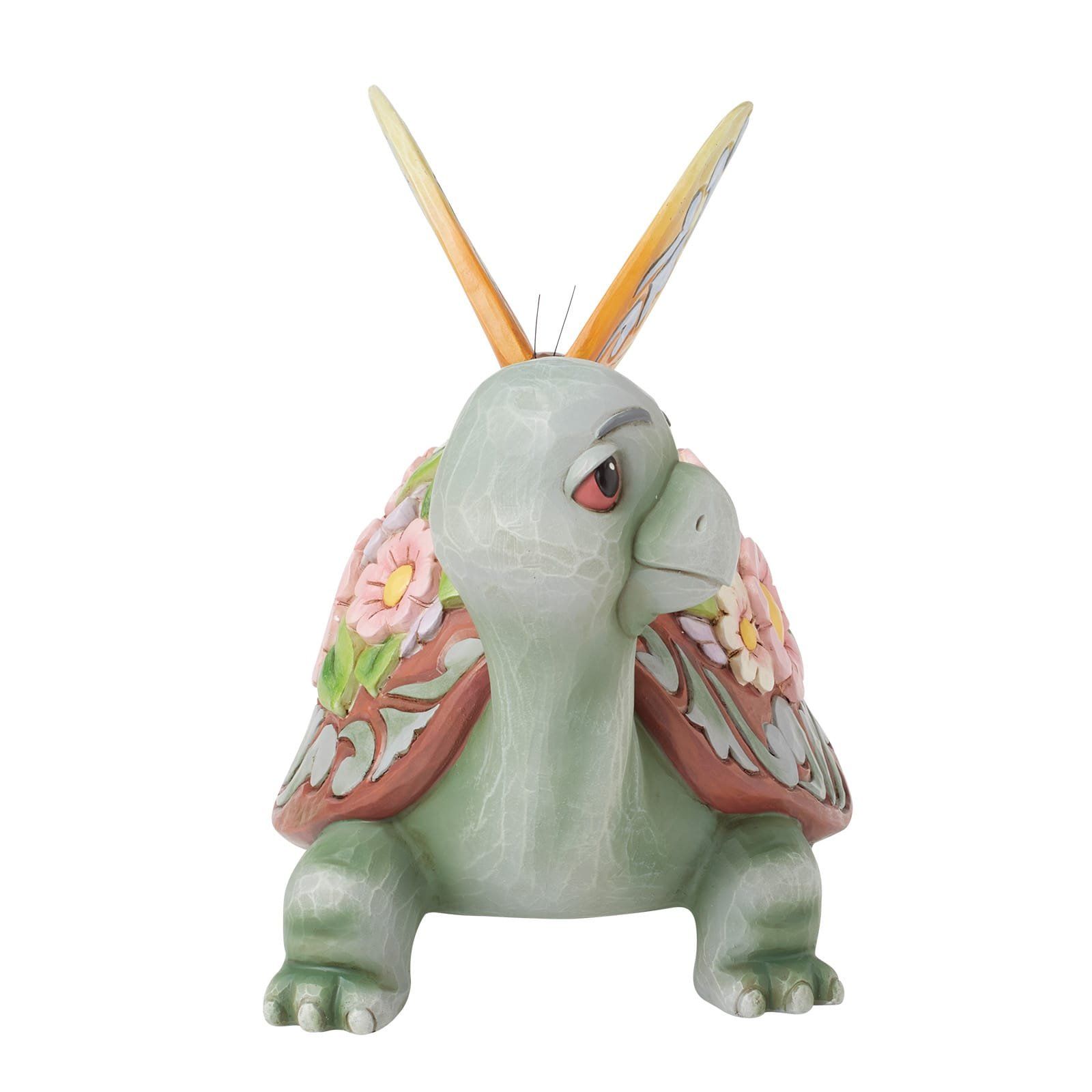 Een beeldje van een schildpad met bloemen op zijn schild