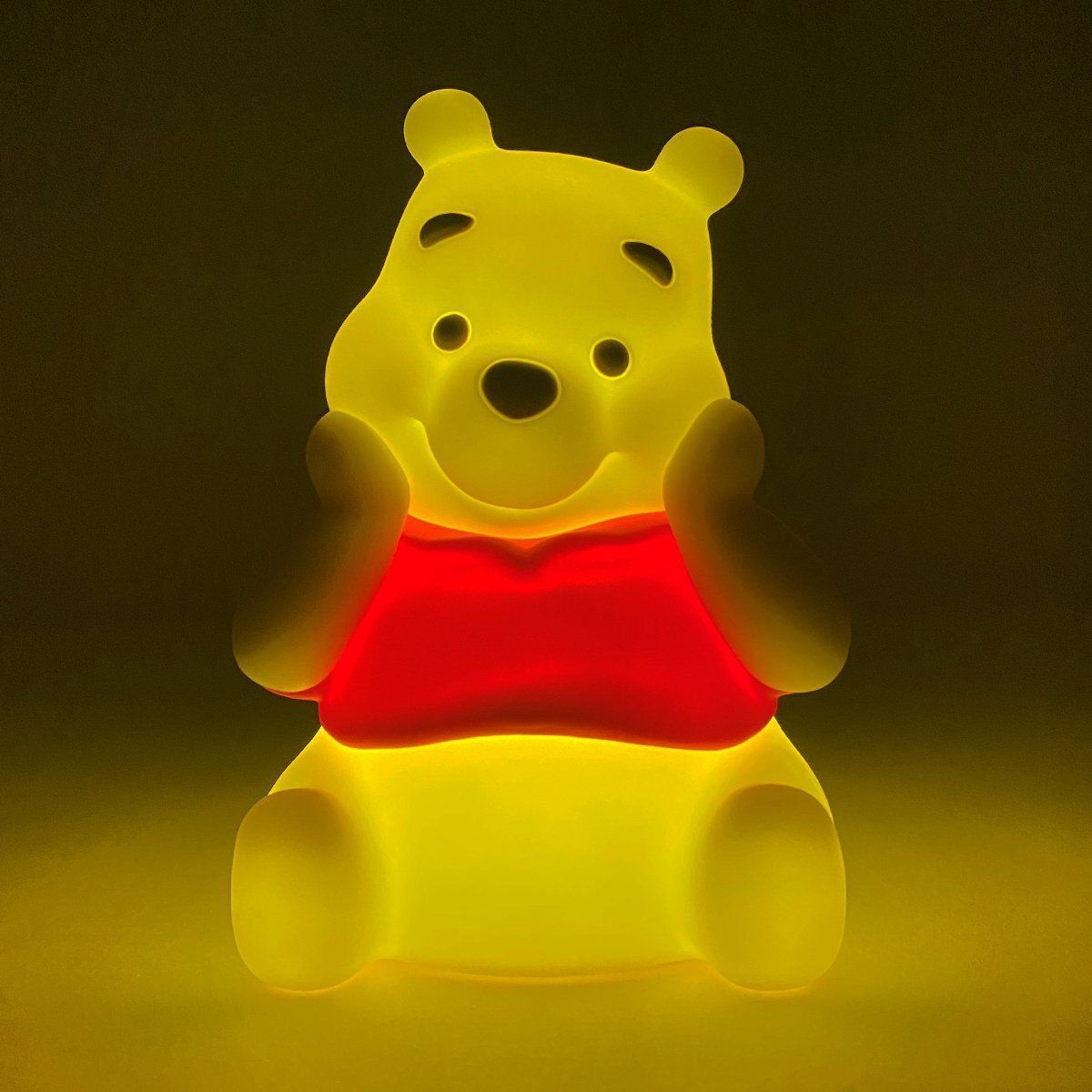 Lichtgevend geel Winnie de Pooh-nachtlampje met rood shirt.