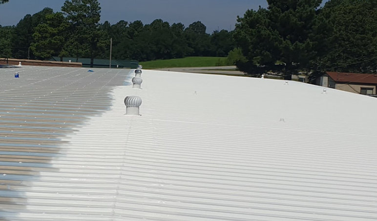 A white, corrugated metal roof under a blue sky, featuring several small, circular rooftop vents in a line.