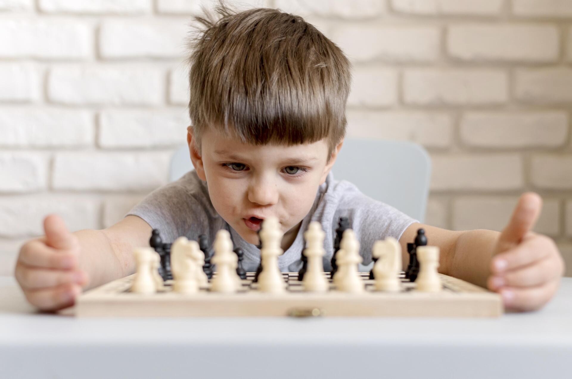 boy looking at chess board with expression on his face