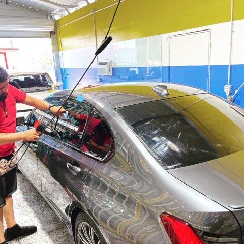 Man Working on a Black Car — Sacramento, CA — Low Cost Auto Glass & Window Tinting