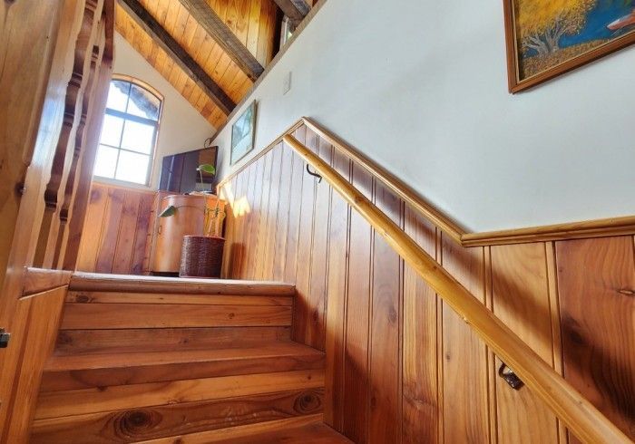 Wooden staircase with railing and paneling, leading up to a window and upper level.