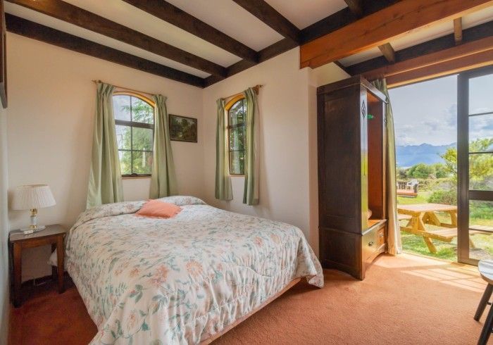 Bedroom with bed, closet, and open door to a patio with a picnic table and scenic view.