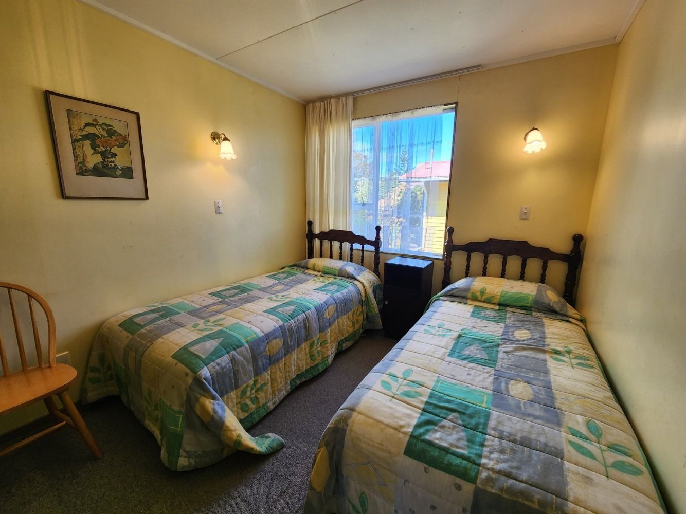 Two twin beds in a room with light yellow walls and a window.